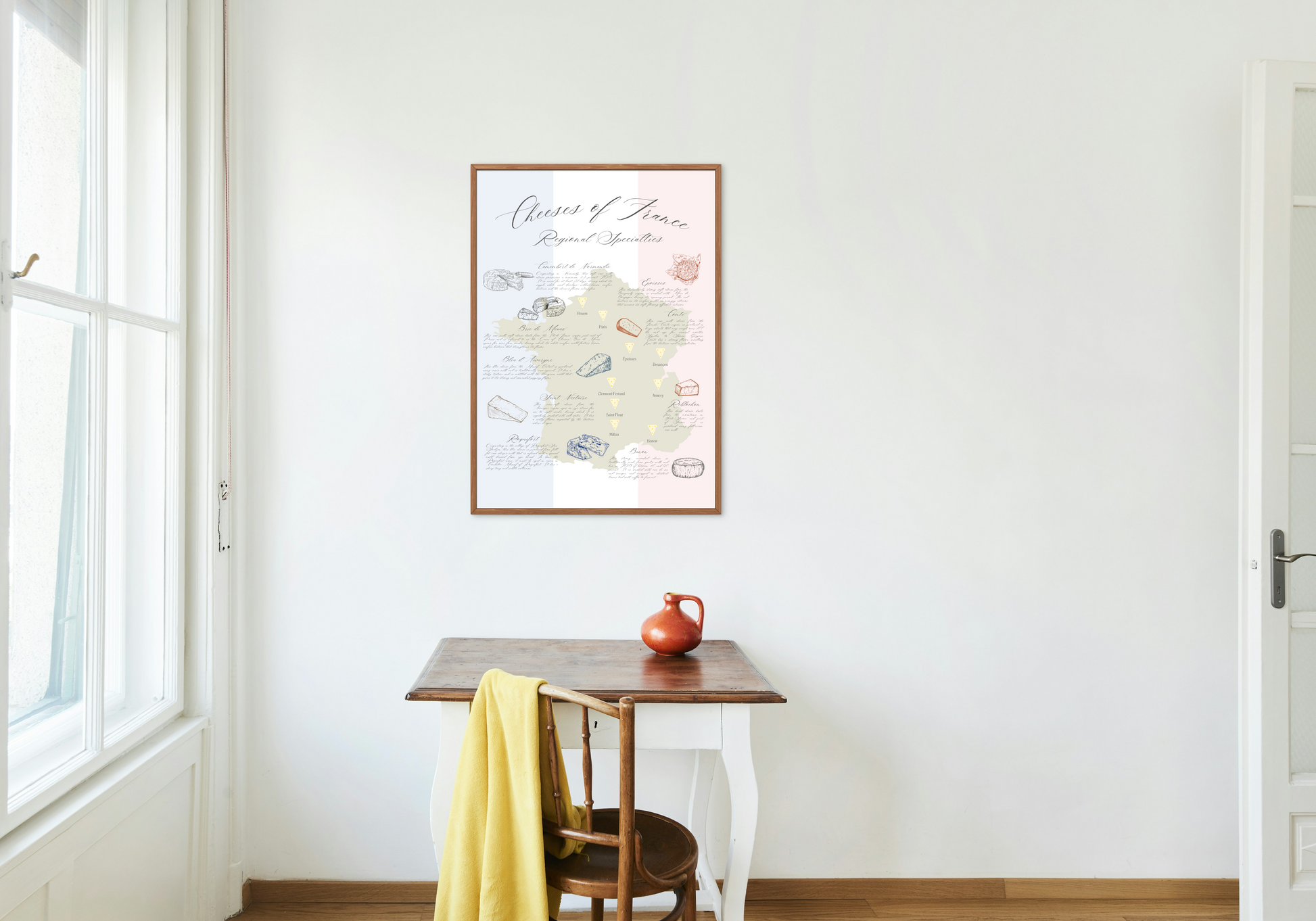 French cheese map art print hanging above a small wooden table in a home.